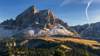 The Würzjoch as a Dolomites holiday Tip: The imposing peak of the Würzjoch in Italy, in front of which alpine meadows extend, radiated by the sun.