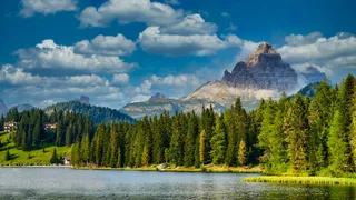 Lake Misurina in the Dolomites in South Tyrol is a great secret tip: A photo from the shore of the lake shows the clear water, surrounded by meadows, trees and mountains