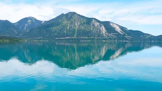 Blick vom Wasser aus auf den türkisblauen Walchensee in Oberbayern und die Berge