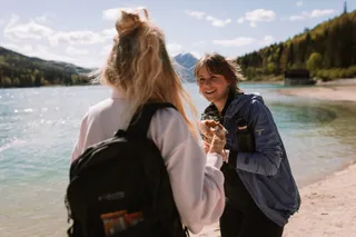 Two friends stand on the shores of Lake Walchen and laugh