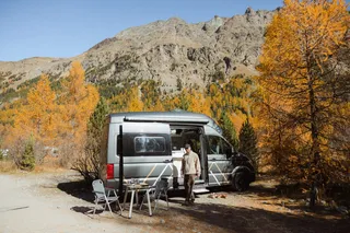 Ein Mann steht beim Camper in den Bergen in Italien