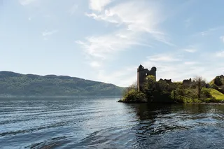 Der Loch Ness mit der Ruine von Schloss Urquhart an seinem Ufer.