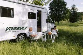 Menschen entspannen sich am Camper und trinken Kaffee