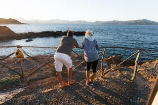 Majorca as a destination in April: A man and a woman stand at sunset overlooking the sea on the coast of Mallorca